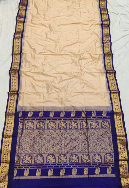 Cream silk Gadwal saree with navy blue border, peacock pallu and all-over butta