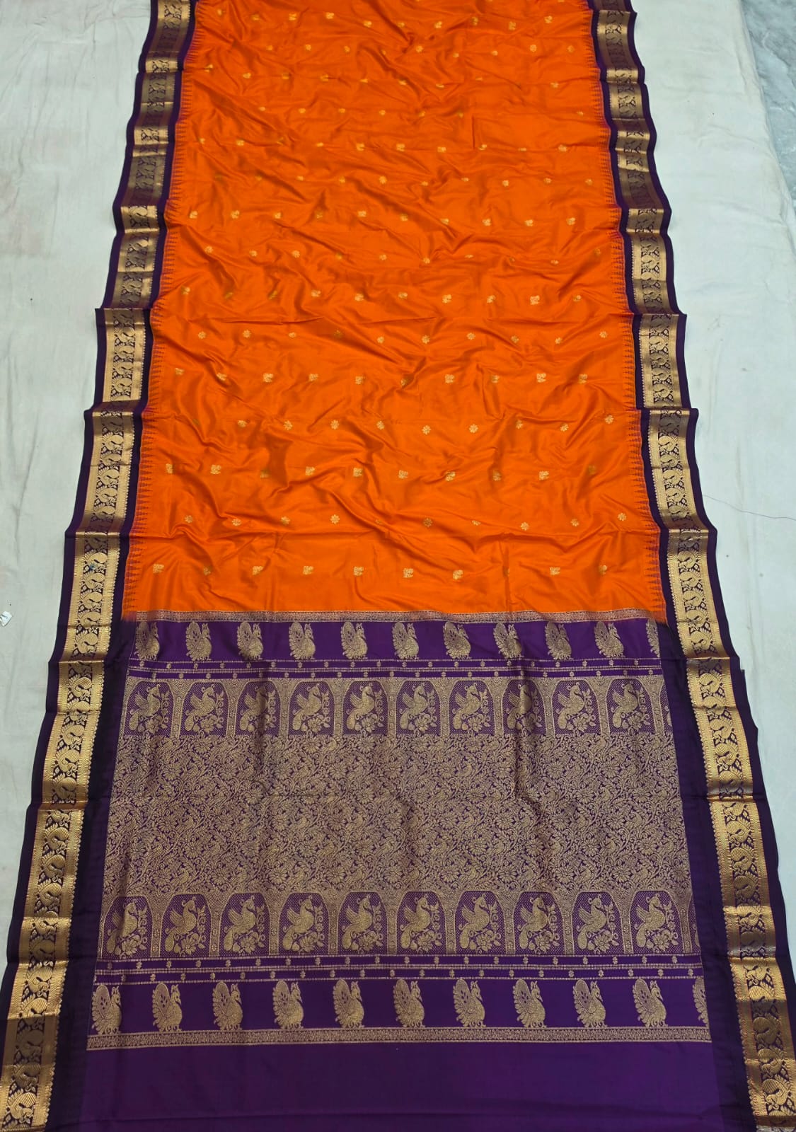 Orange silk Gadwal saree with purple border, peacock pallu and all-over butta