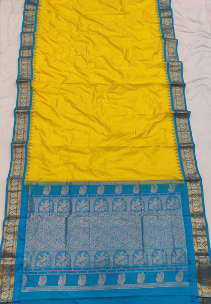 Yellow silk Gadwal saree with sky blue border, peacock pallu and all-over butta